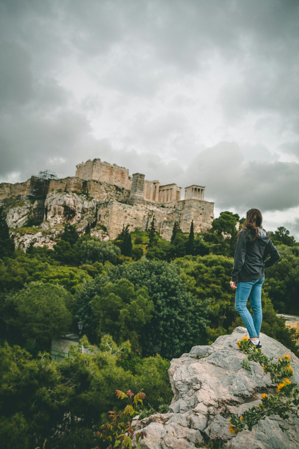 woman standing on rock near green trees