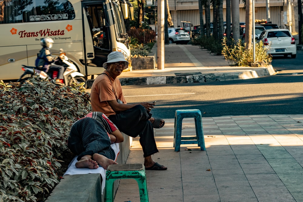 old man sitting near woman lying on pavement