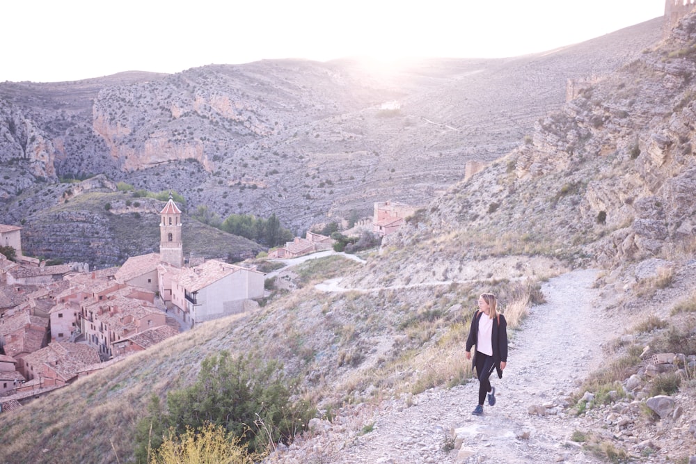 Mujer con cárdigan negro caminando en el campo rocoso