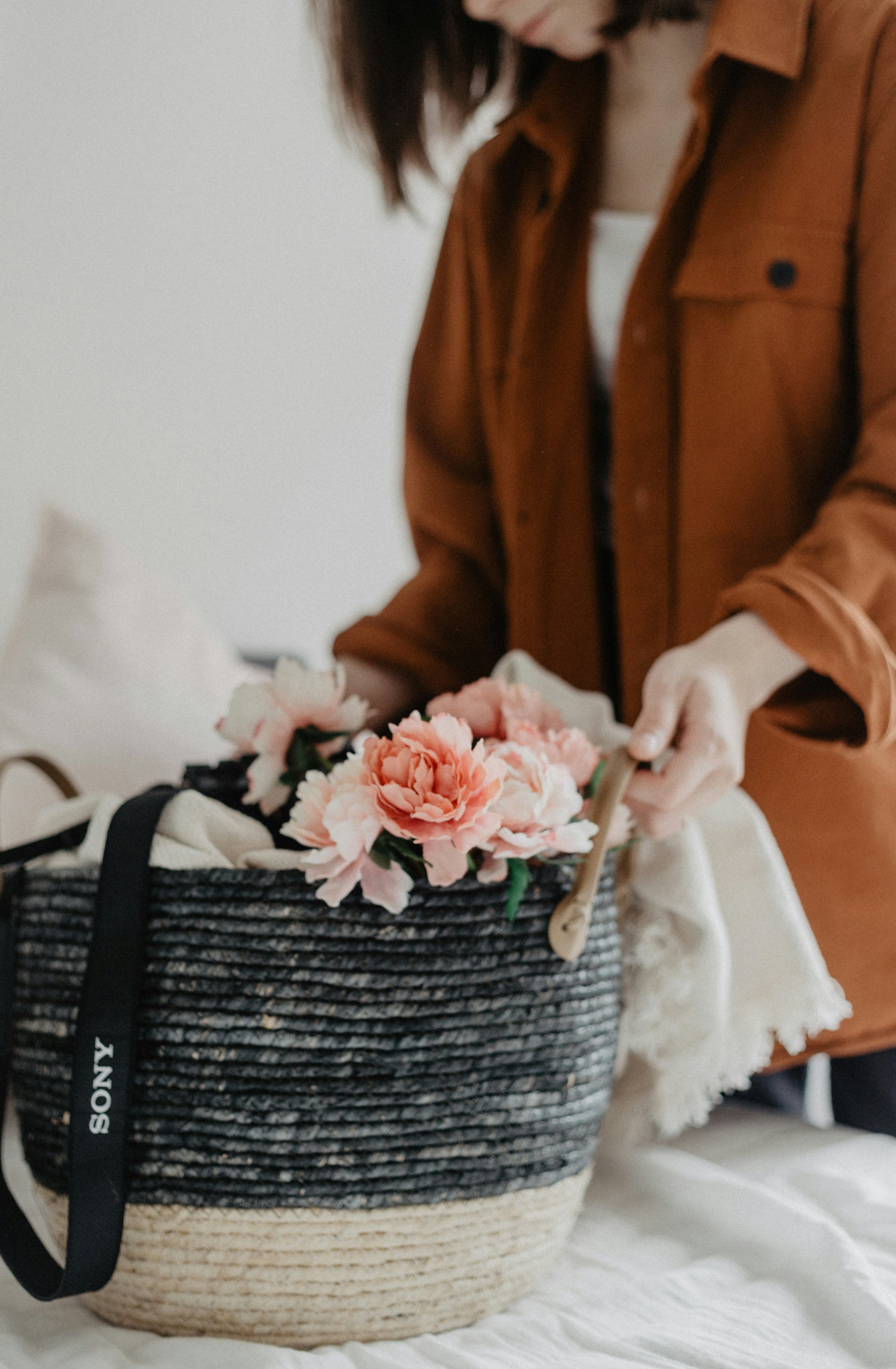 woman standing beside basket of flowers on white textile