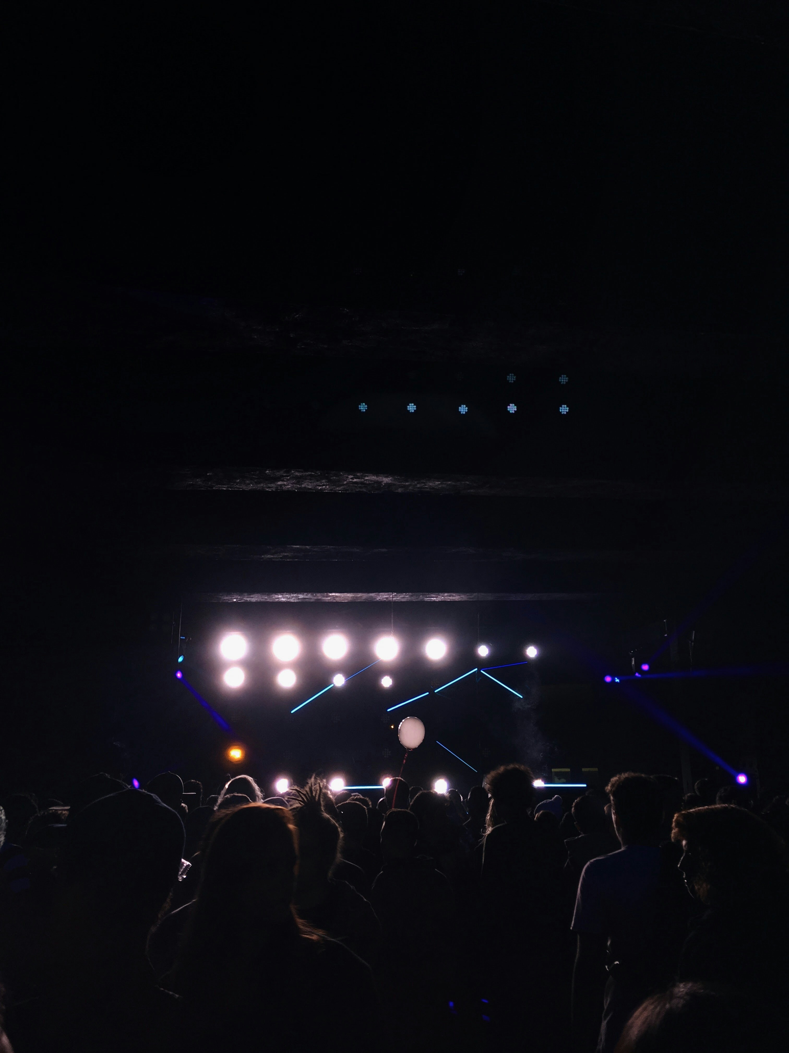 Neon-lit concert stage with holographic light beams and crowd silhouettes in a futuristic venue