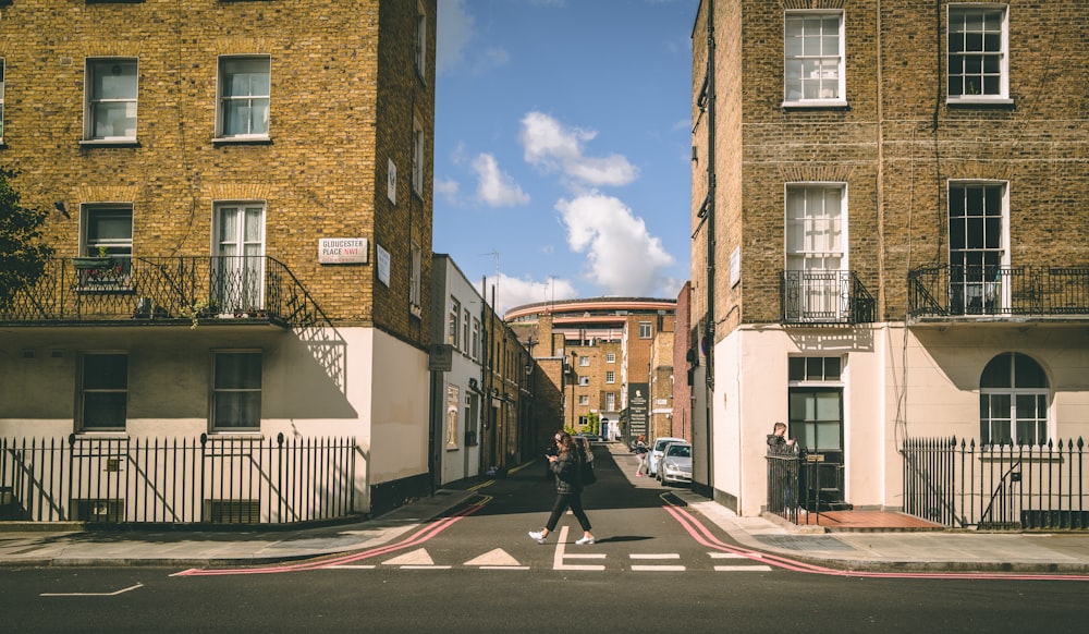 person crossing on street between buildings