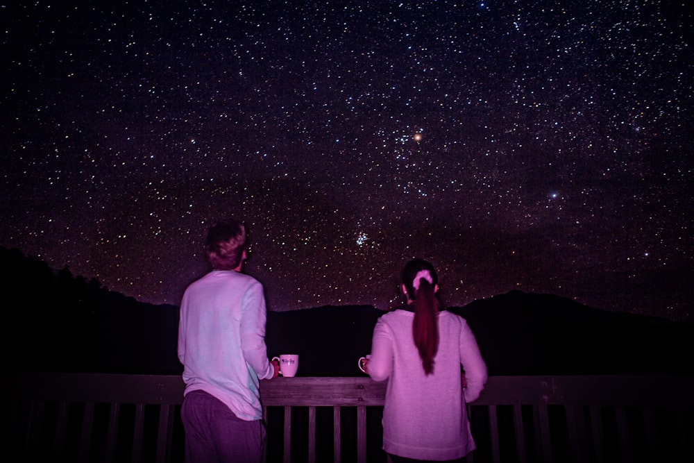man and woman standing in front of galaxy