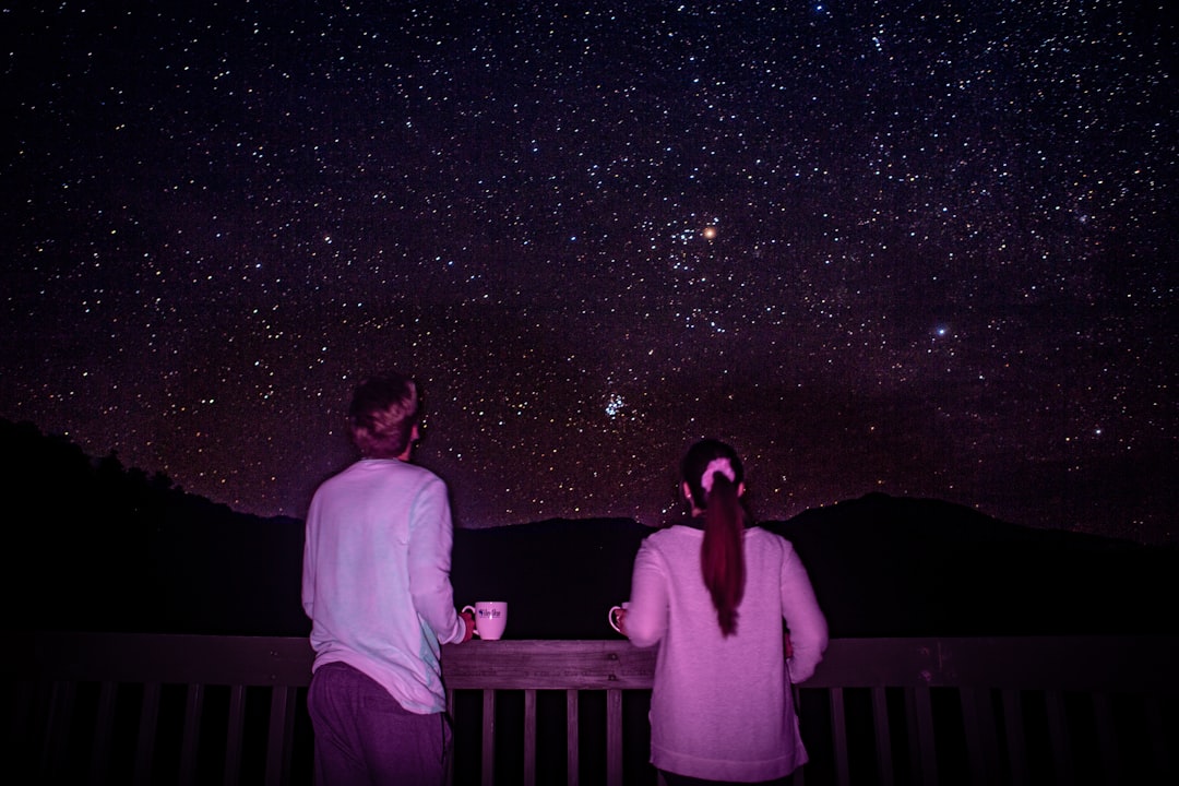man and woman standing in front of galaxy,