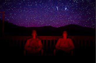 two men sitting under starry sky during nighttime