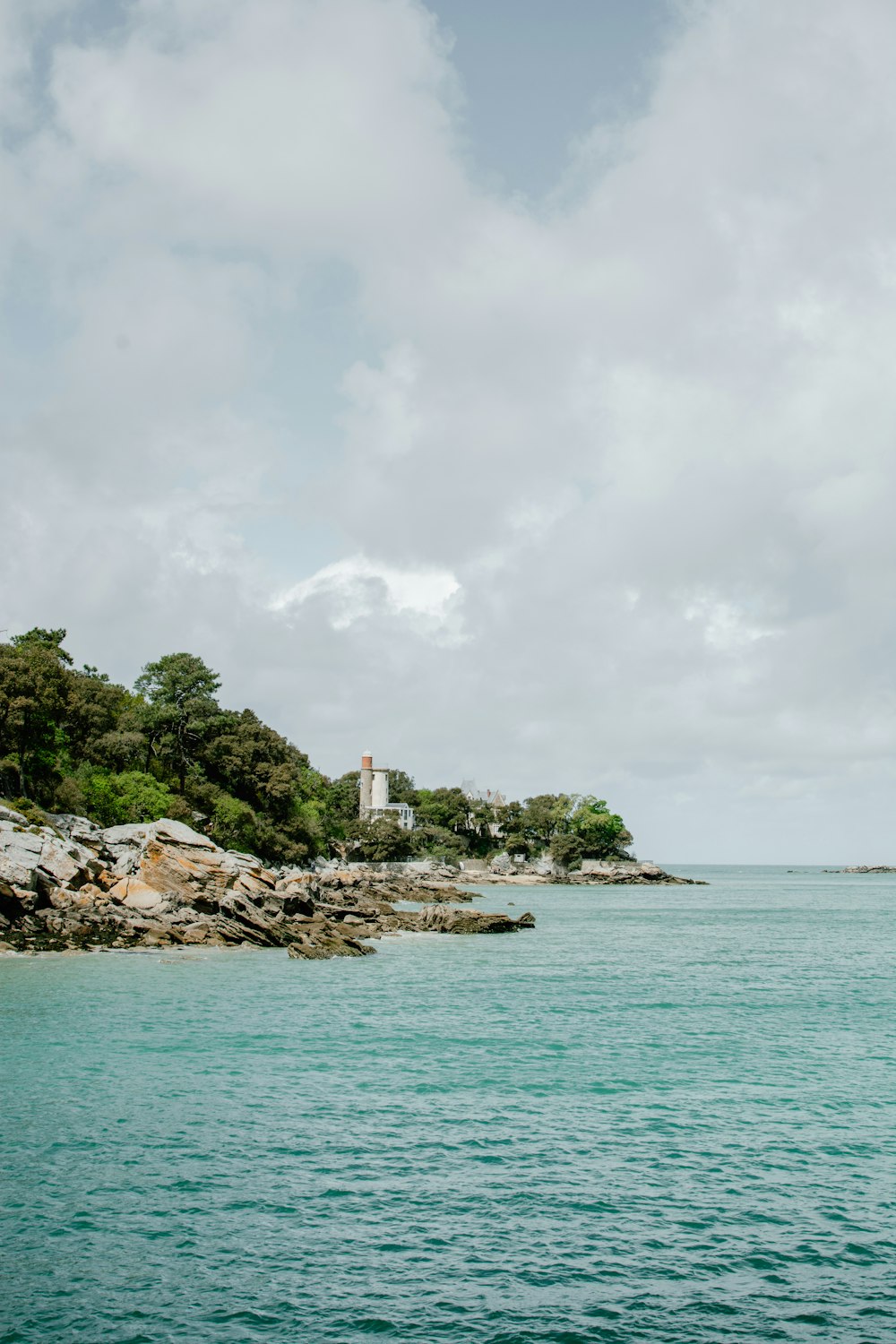 white and orange lighthouse in rocky beach