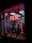 A storefront features a prominently displayed neon sign with the word 'PSYCHIC' in bright red. The window is adorned with red string lights and contains various decorative items, including statues and plants. A poster inside provides additional information on psychic services.
