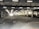 An indoor loading dock area with a large, open space. Fluorescent lights are affixed to the ceiling, illuminating the area. A white delivery truck is parked on the right side near a section with loading bays. The area appears industrial, with exposed concrete floors and columns.