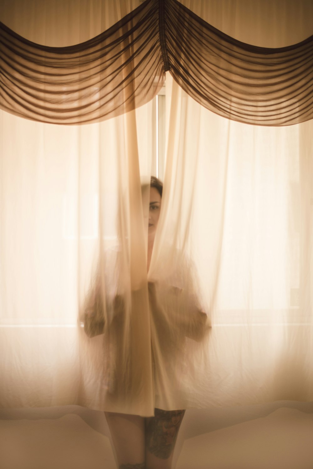 woman hiding in window curtains