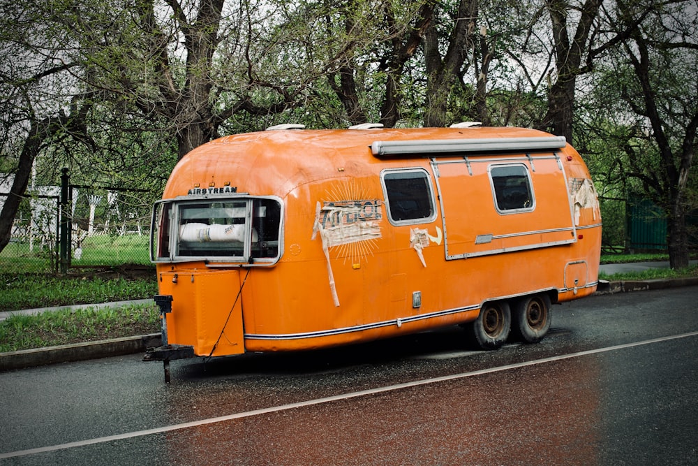 travel trailer on road beside trees