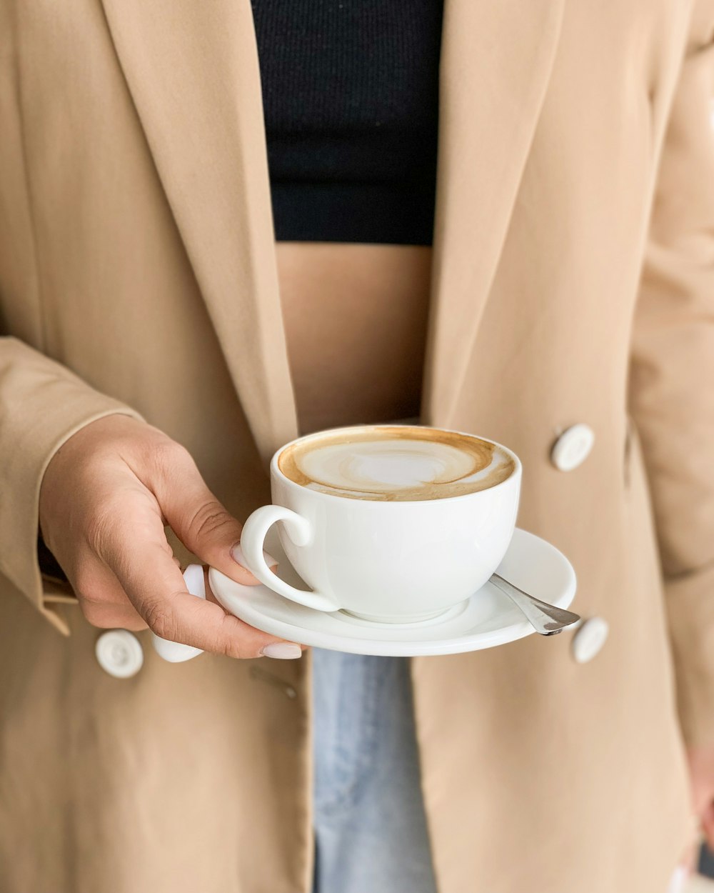 persona sosteniendo una taza de cerámica blanca llena de café