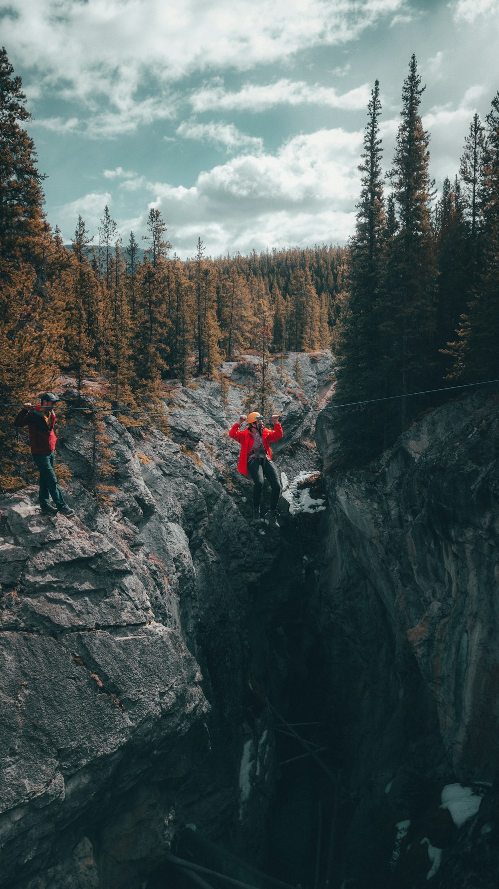 two person walking on cable under white clouds