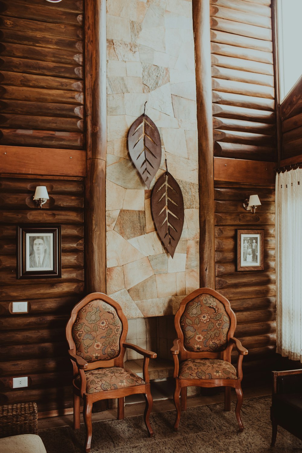 two empty armchairs beside wooden wall