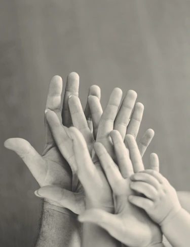 grayscale photo of family's hands