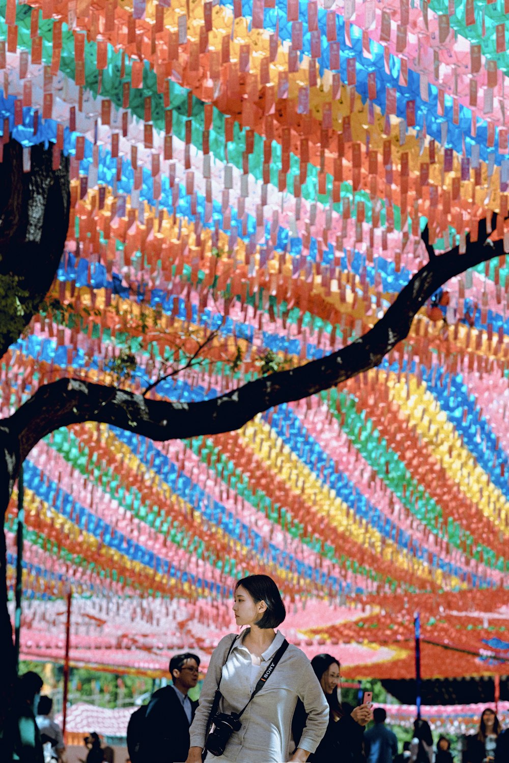 people walking under multicolored hanging decors