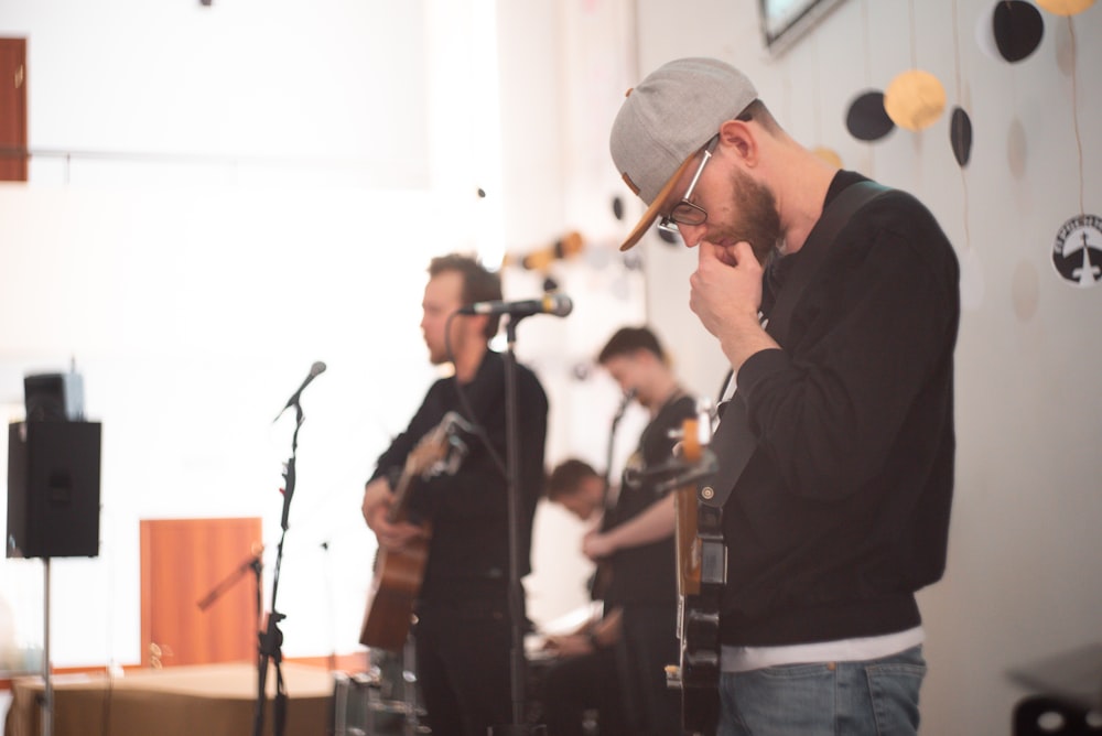 man wearing black crew-neck sweater playing guitar