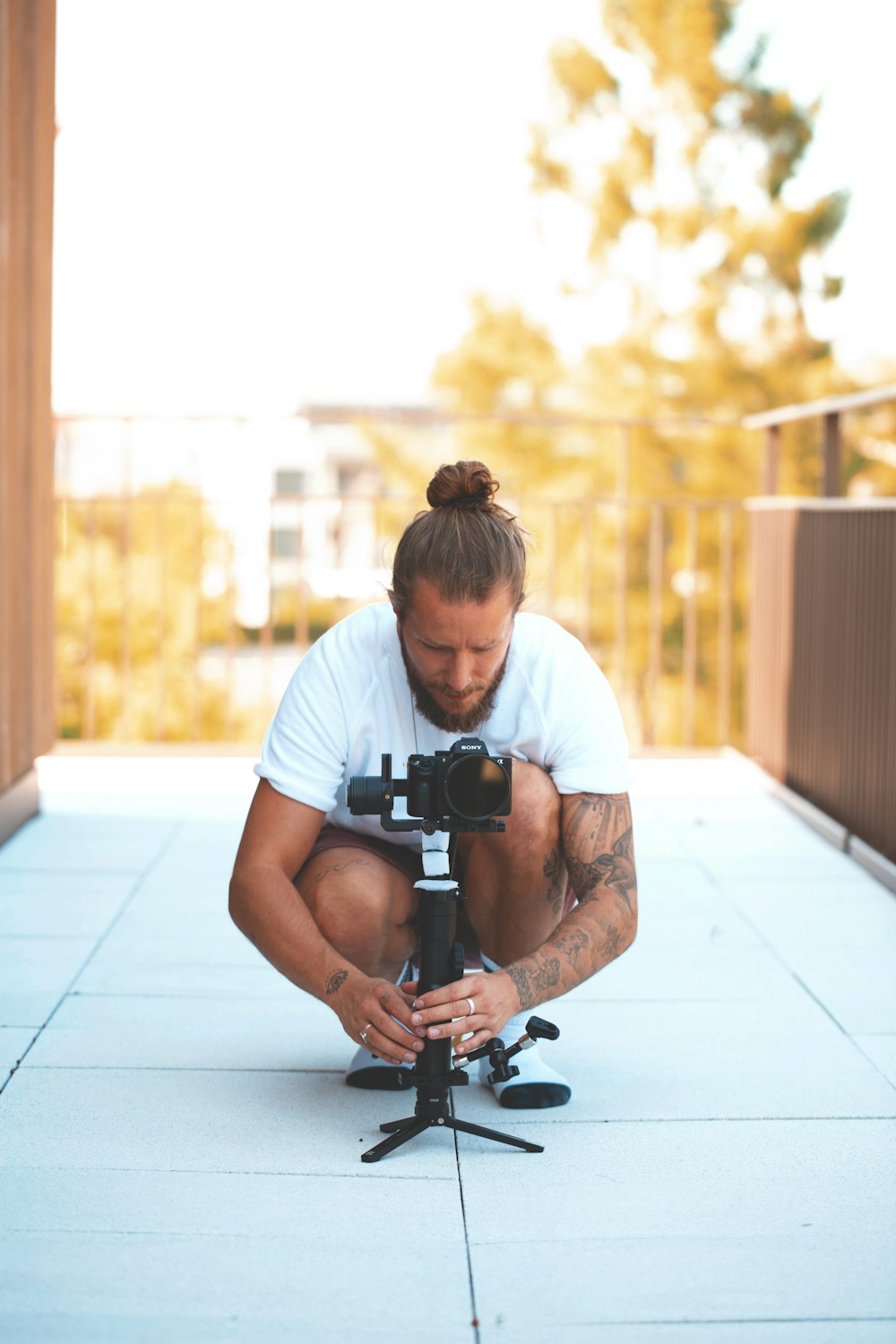 shallow focus photo of man in white T-shirt using DSLR camera