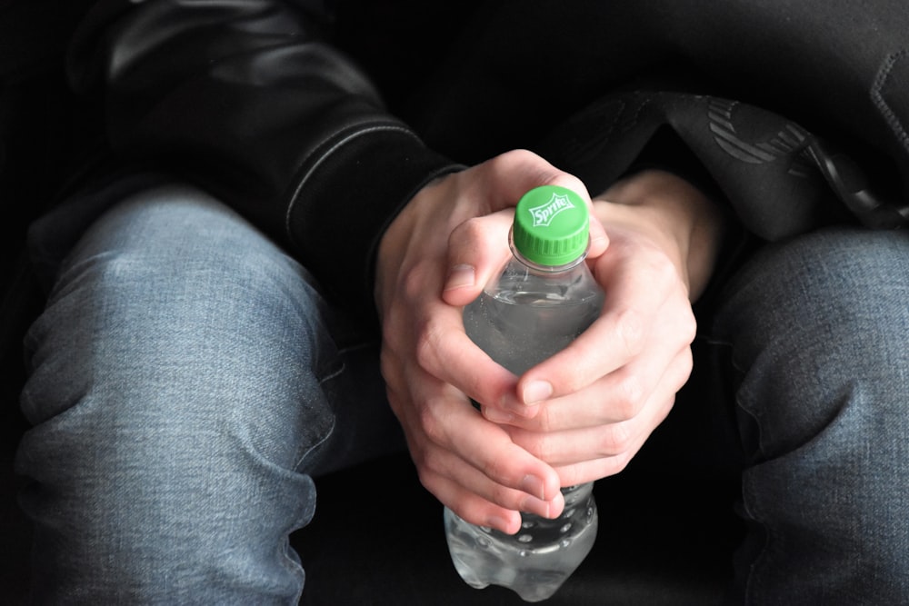 close-up photo of sitting person holding bottled water