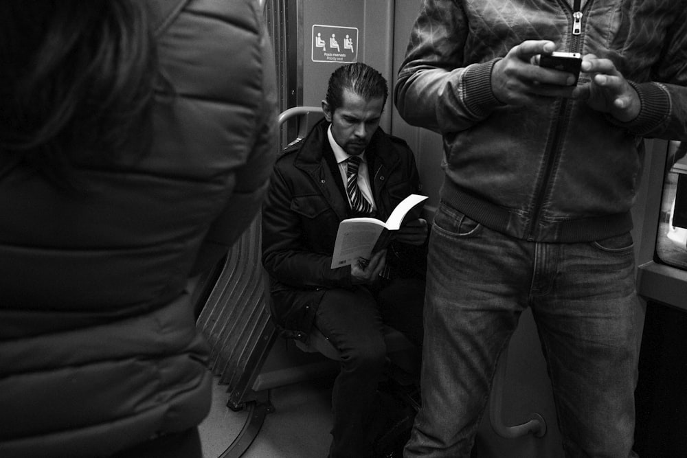 grayscale photo of man reading book