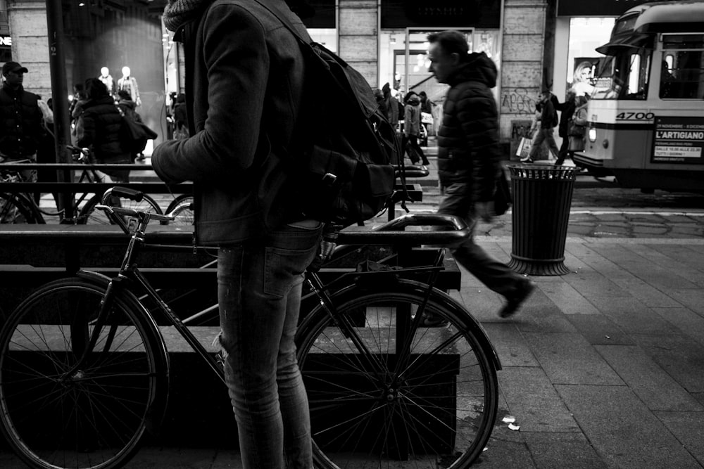 grayscale photography of person beside bicycle