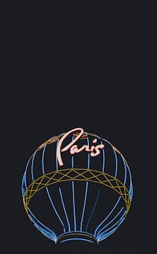 A neon-style illustration of a hot air balloon with the word 'Paris' written in bright, glowing red letters at the top. The balloon features outlines in blue and yellow, set against a completely black background.