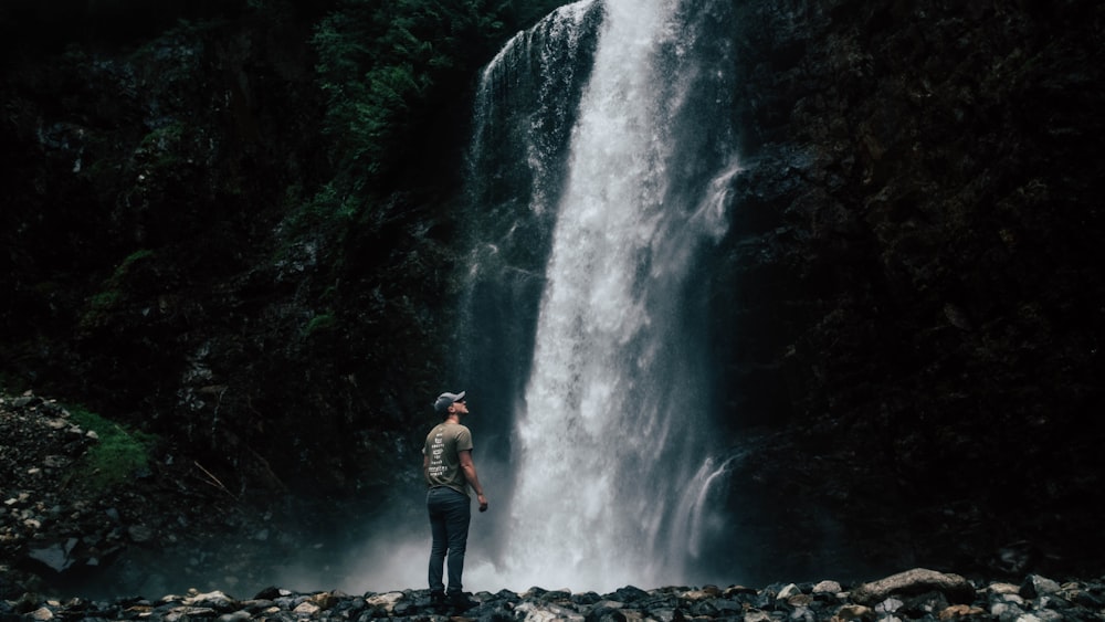 man standing in front of waterfall looking up