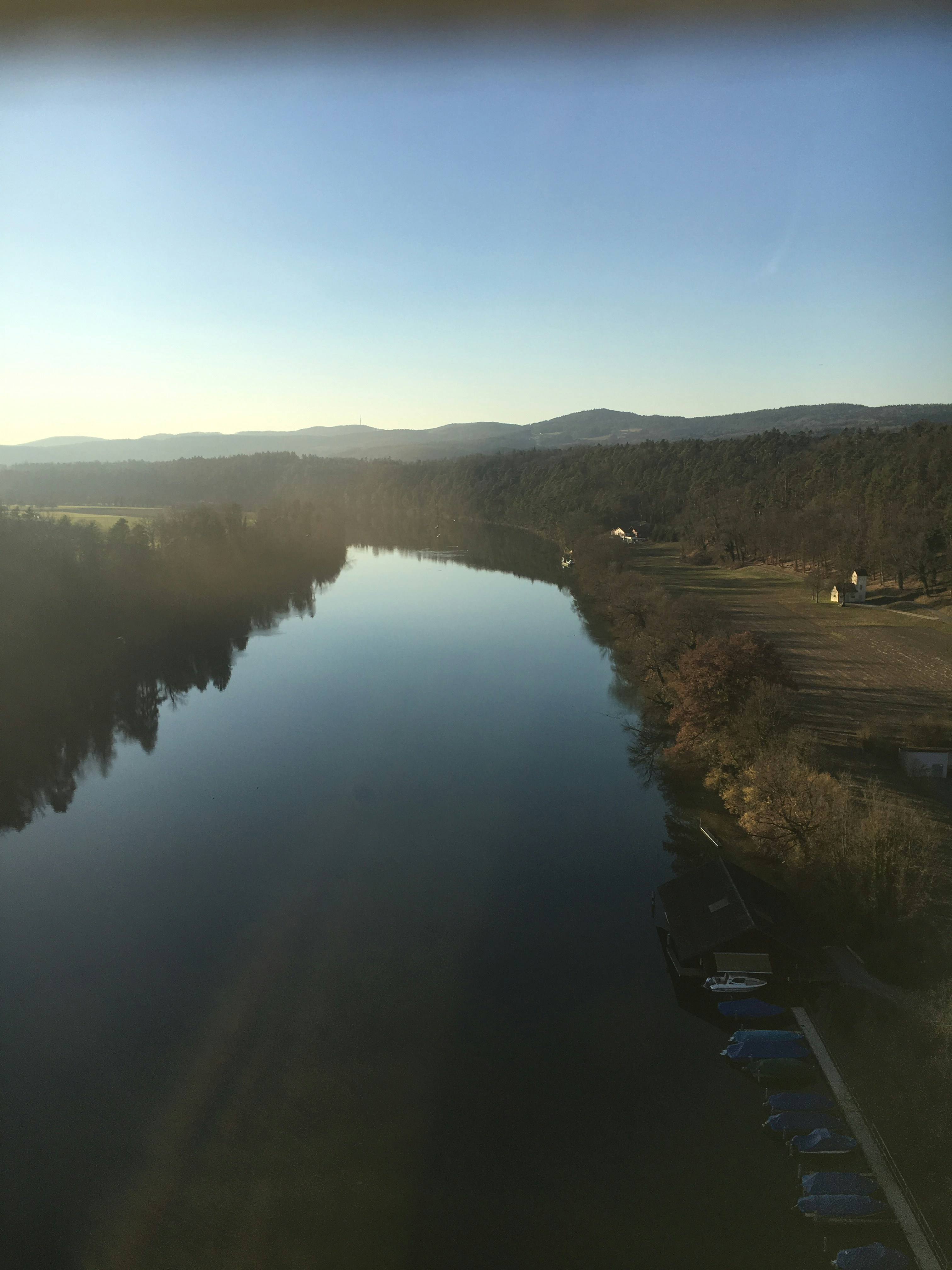 Calm river water reflecting bright sky, open landscape, daylight, clear blue tones