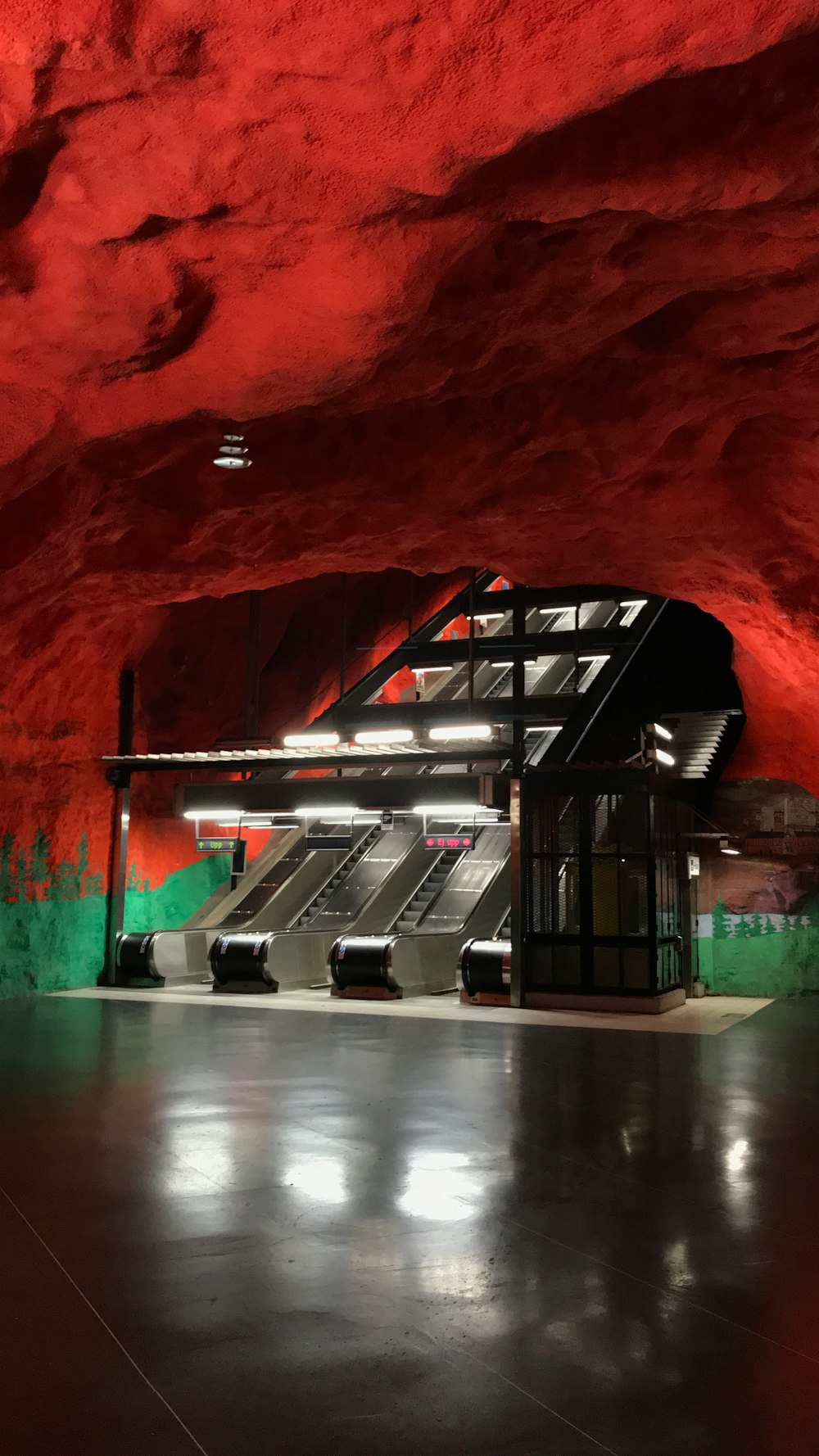 a red and green tunnel with escalators and stairs