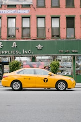 yellow sedan in road near building during daytime