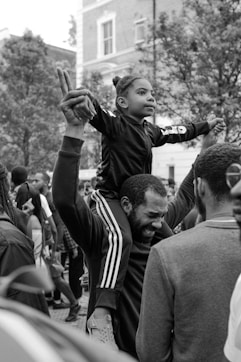 A father carries his daughter on his shoulders, preserving family history through shared stories.