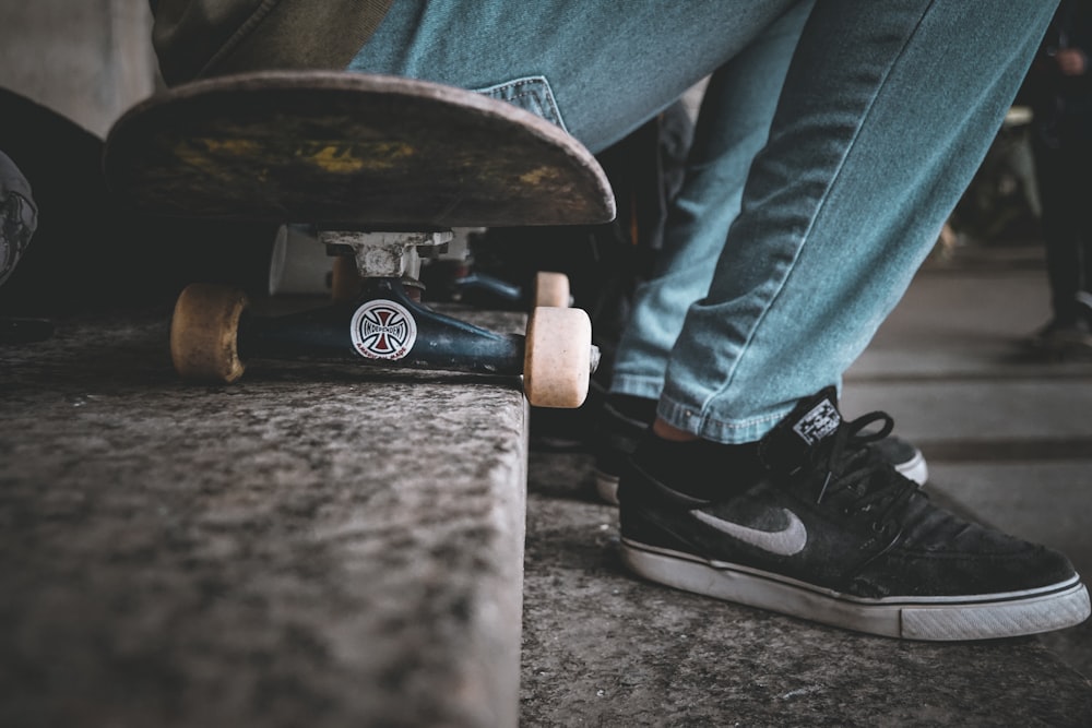 unknown person sitting on black skateboard outdoors