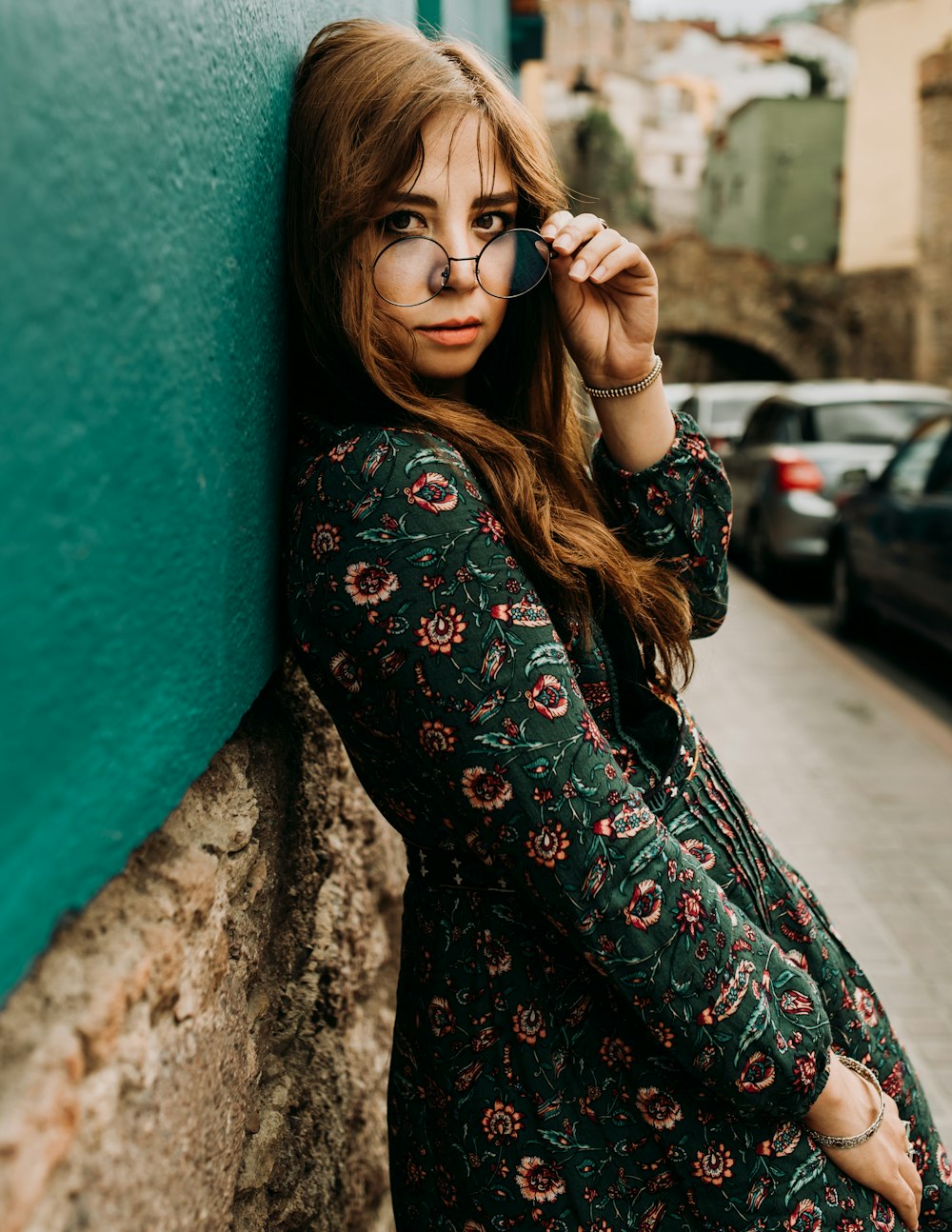 mujer con vestido verde apoyado en la pared