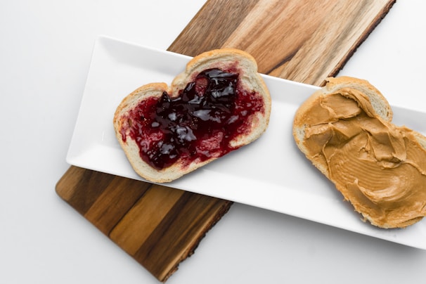 A cyclist spreading peanut butter on a slice of whole grain bread at a roadside rest stop.