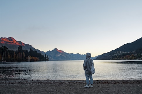 A serene photo of a person wearing an Imperial 33 hoodie, standing peacefully in nature at sunrise.