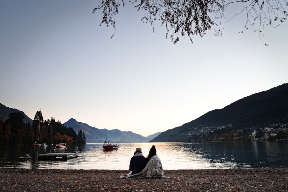 man and woman sitting on sea shore