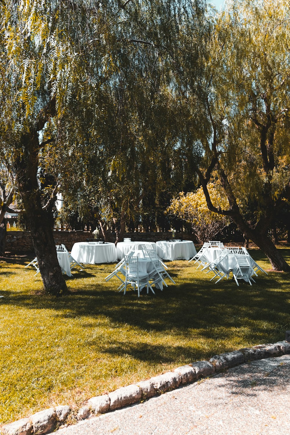 white outdoor tables and chairs outside near trees