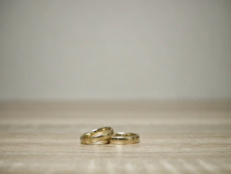 A minimalist gold ring set displayed on a smooth black marble surface.