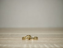 A minimalist display of gold rings and bracelets arranged on a marble surface.