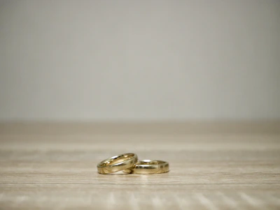Minimalist shot of a stack of thin gold rings with smooth curves on a marble surface.