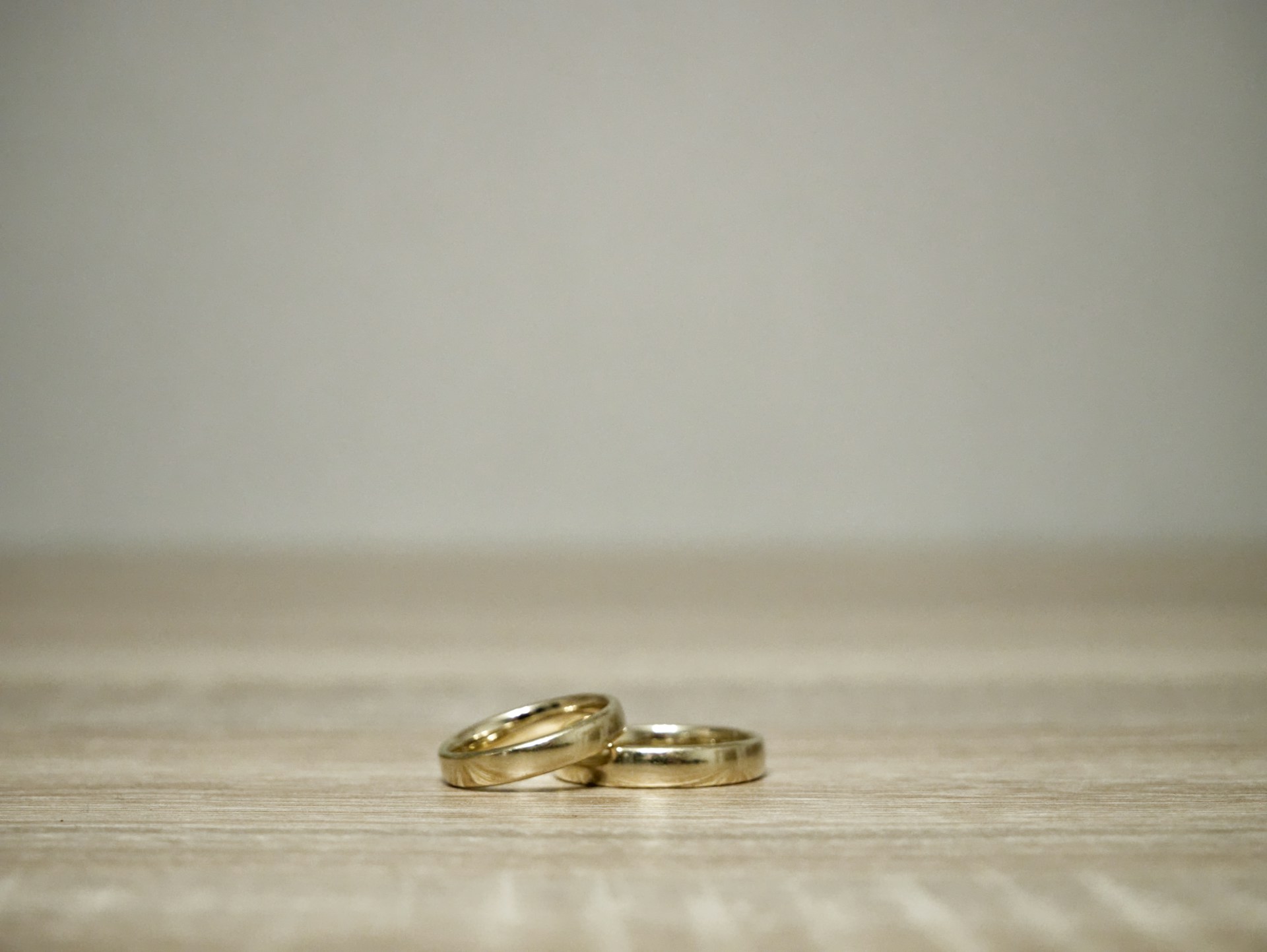 A close-up of elegant women's gold and silver rings on a minimalist white surface.