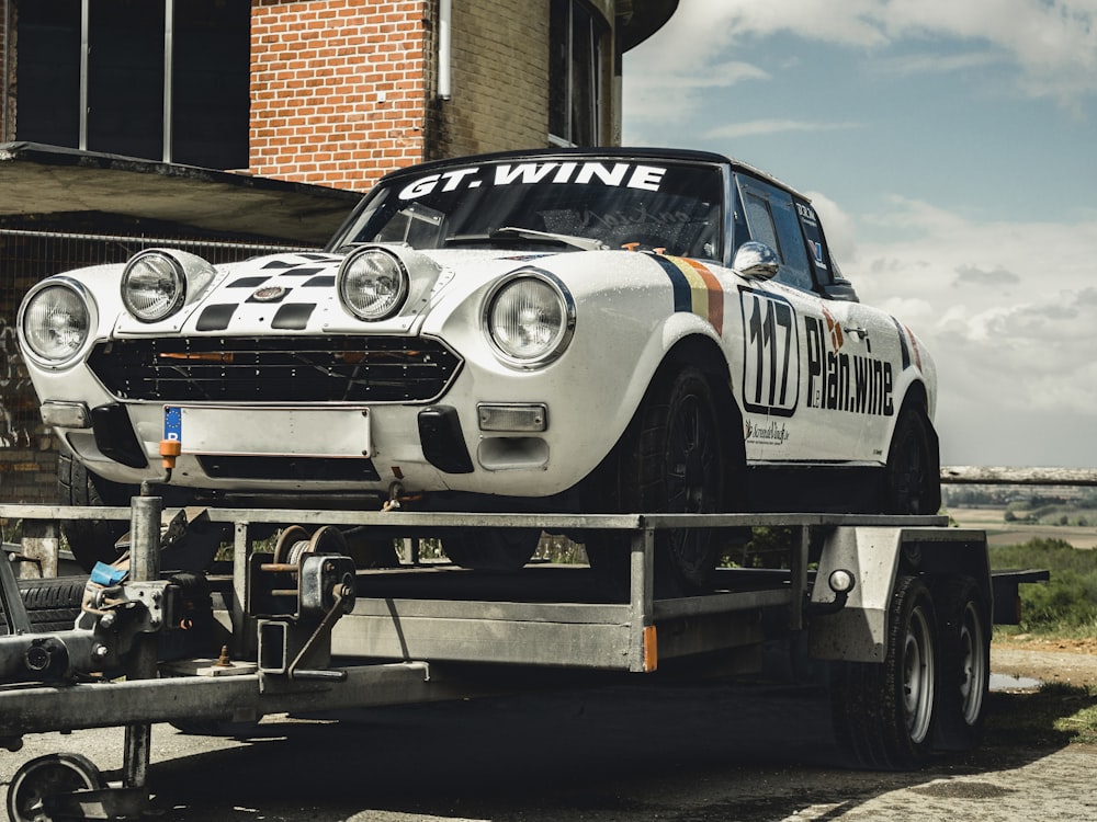 white and black coupe on trailer during daytime