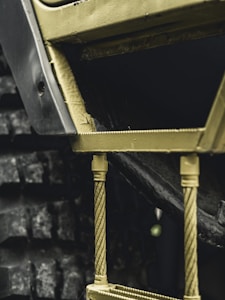 Close-up view of a textured industrial machinery component, featuring metal rods and a section of a treaded wheel.