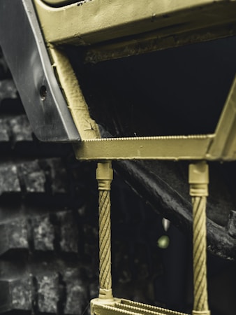 Close-up view of a textured industrial machinery component, featuring metal rods and a section of a treaded wheel.