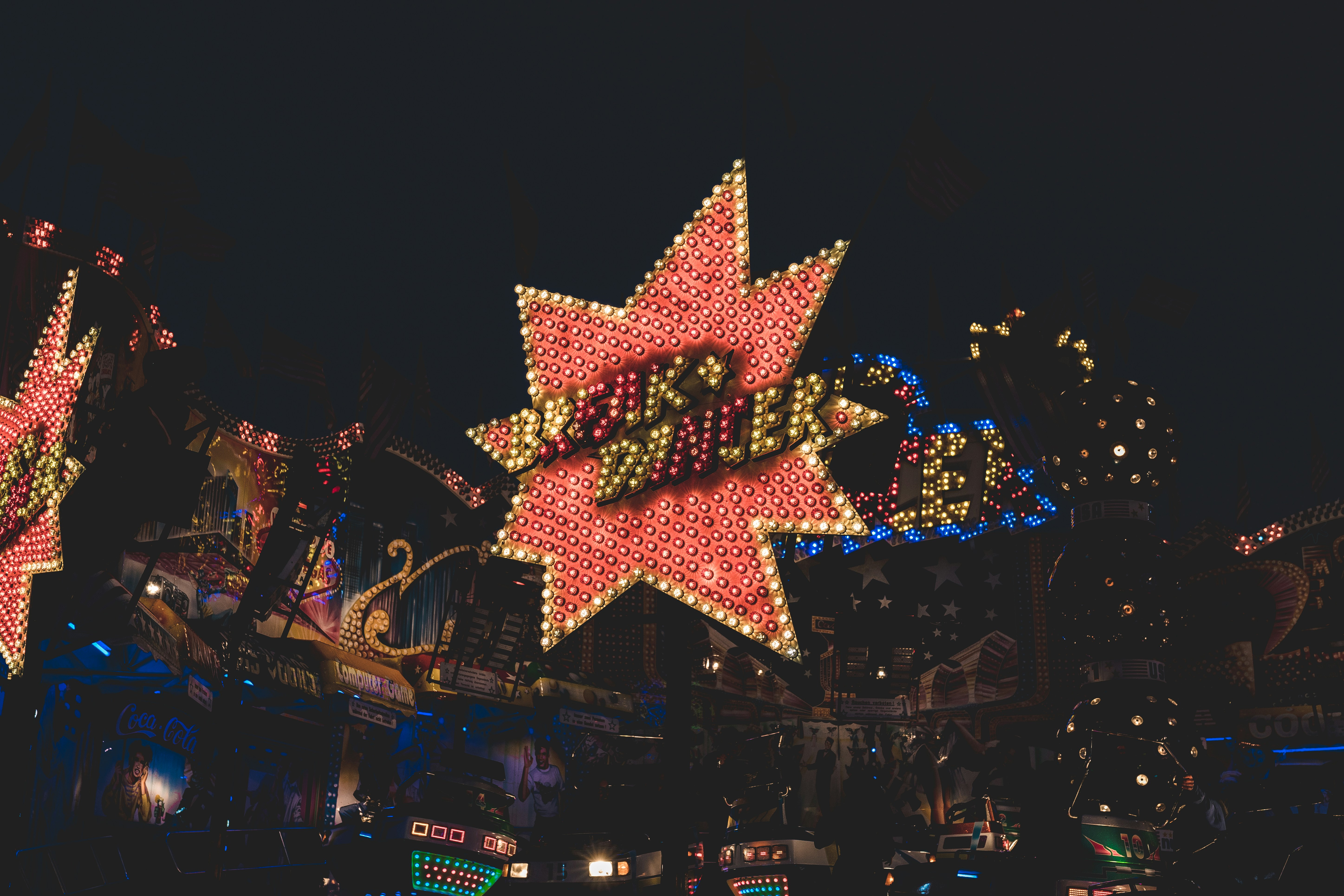 A glowing red-and-yellow star funfair sign lit up at night at the Munich Spring Festival