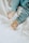A close-up view of a child's legs and feet wearing light blue pajamas on a soft, white crumpled fabric background.