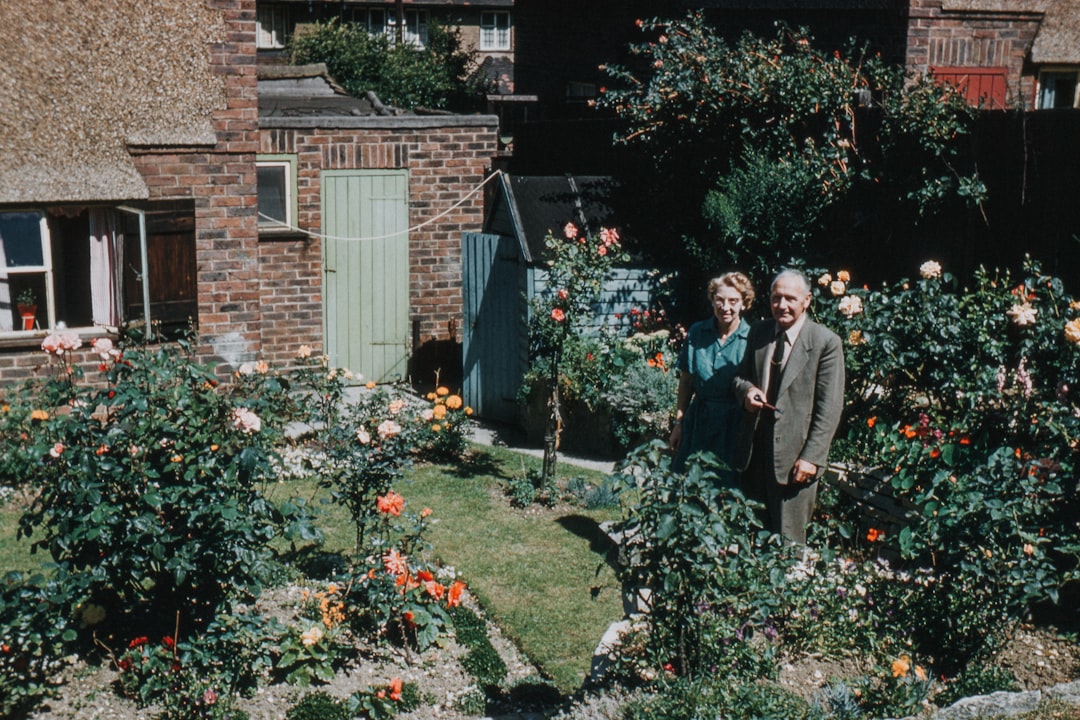 two man and woman standing near flowers and building
