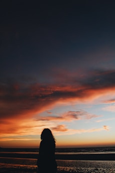 silhouette of woman walking on seashore