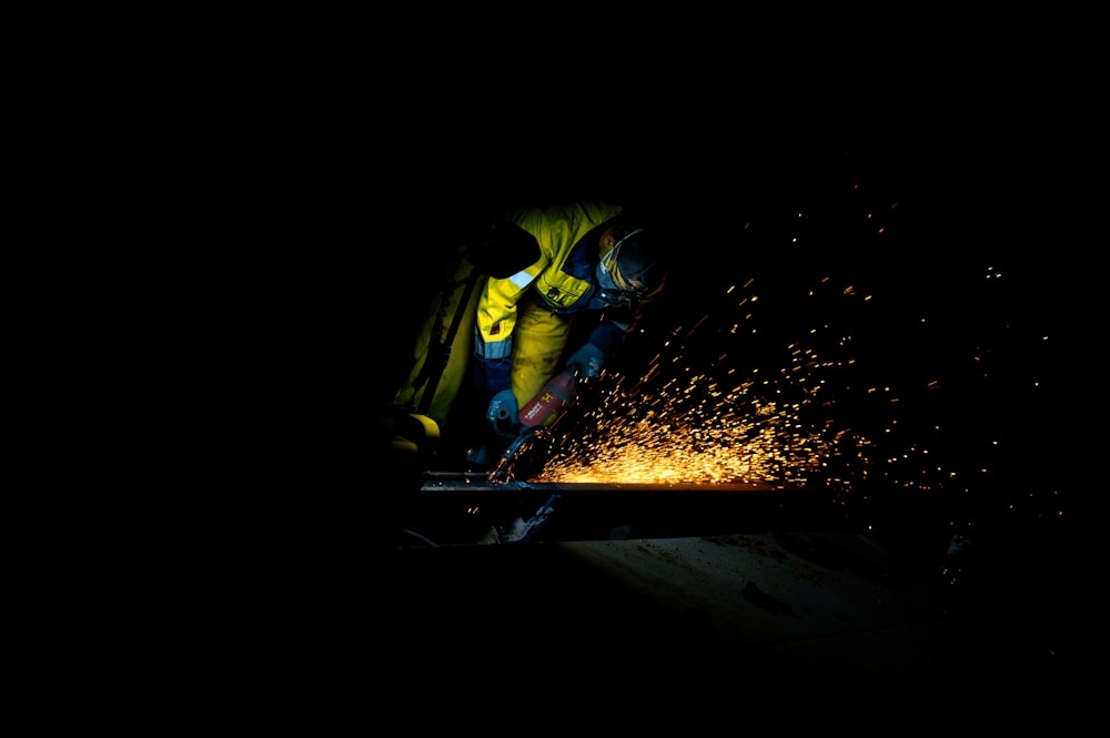 a man in a yellow vest working on a piece of metal