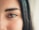 A close-up of a human eye with long eyelashes and a well-defined eyebrow. The skin is smooth, and there is a subtle presence of blush or natural redness on the cheek area.