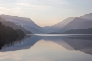 A tranquil lake reflecting the mountains at sunrise.